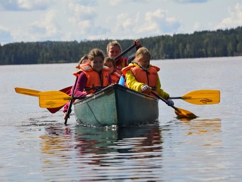 Kinder sind in einem Kanu und paddeln über den See