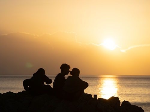 Gäste am Strand beim Sonnenuntergang